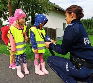 Zdjęcie przedstawia policjantkę, która wręcza dzieciom odblaski.