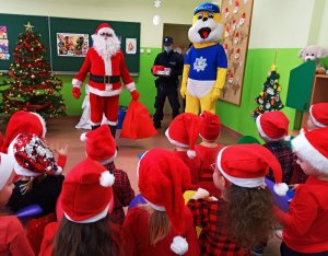 Zdjęcie przedstawia Św. Mikołaja, maskotkę opolskiej Policji oraz policjanta w otoczeniu dzieci.