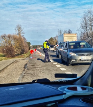 Zdjęcie przedstawia umundurowanego policjanta ruchu drogowego na granicy polsko-białoruskiej, podczas kontroli drogowej.