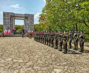 Zdjęcie przedstawia żołnierzy pod Pomnikiem Czynu Powstańczego na Górze Św. Anny, w tle flagi Polski.