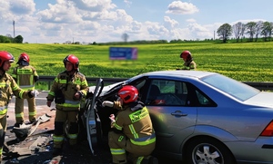 Zdjęcie przedstawia strażaków wyciągających zakleszczoną osobę z pojazdu.