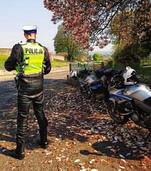 Zdjęcie przedstawia motocyklistę, który sprawuje nadzór nad droga, obok niego policyjny motocykl.