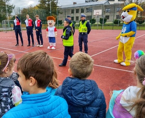 Zdjęcie przedstawia dzieci, policjantów, siatkarzy Zaksy Strzelce Opolskie oraz maskotkę drużyny oraz opolskiej policji podczas spotkania profilaktycznego z dziećmi.
