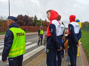 Zdjęcie przedstawia dzieci, policjantów, siatkarzy Zaksy Strzelce Opolskie oraz maskotkę drużyny oraz opolskiej policji podczas ćwiczeń prawidłowych zachowań na przejściu dla pieszych.