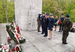 Zdjęcie przedstawia czterech przedstawicieli służb mundurowych oddających hołd przed pomnikiem.