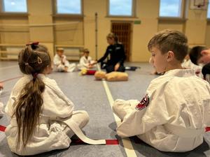 Zdjęcie przedstawia zajęcia z pomocy przedmedycznej z udziałem młodych karateków.