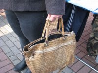 Kobieta podczas zakupów na targowisku ma otwartą torebkę