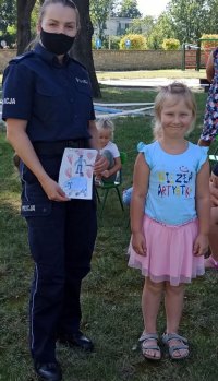 Policjantka pozuje do zdjęcia trzymając w ręku laurkę wręczoną przez dzieci