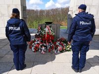 Zdjęcie przedstawia policjantów stojących przy Pomniku Czynu Powstańczego na Górze św. Anny, przed nimi leżą złożone wieńce kwiatów.