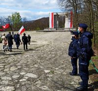 Zdjęcie przedstawia uczestników uroczystości zmierzających w stronę Pomnika Czynu Powstańczego, po prawej stronie policjanci zabezpieczający uroczystość.