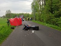 Zdjęcie przedstawia motocykl leżący na ziemi, po zdarzeniu drogowym.