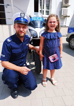 Zdjęcie przedstawia 5-letnią dziewczynkę z policjantem ruchu drogowego.