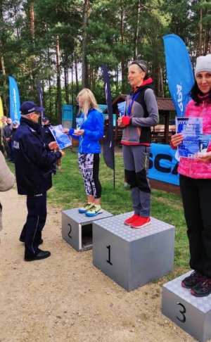 Zdjęcie przedstawia podium wraz zawodnikami oraz policjanta wręczającego medal.