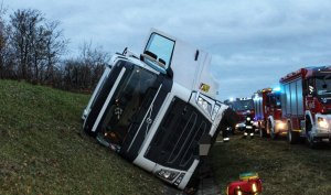 Zdjęcie przedstawia przewróconą ciężarówkę na autostradzie.