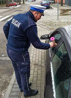 Zdjęcie przedstawia policjanta ruchu drogowego wręczającego kierującej kwiaty.