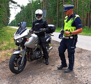 Zdjęcie przedstawia policjanta podczas kontroli motocyklisty.