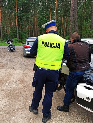 Zdjęcie przedstawia policjanta podczas kontroli motocyklisty.