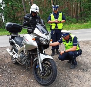 Zdjęcie przedstawia policjantów podczas kontroli motocyklisty.