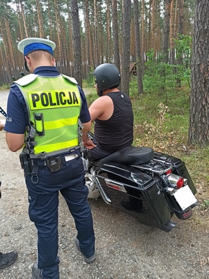 Zdjęcie przedstawia policjanta podczas kontroli motocyklisty.