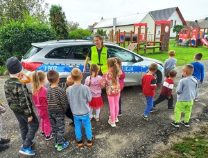 Zdjęcie przedstawia policjantów, prezentujących dzieciom radiowóz.