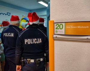 Zdjęcie przedstawia spotkanie policjantów, strażaka, Policusia i Mikołaja z dziećmi w szpitalu.