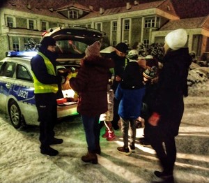 Zdjęcie przedstawia policjantów rozdających odblaski.