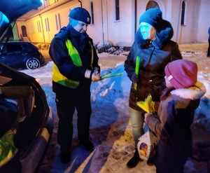 Zdjęcie przedstawia policjantów rozdających odblaski.