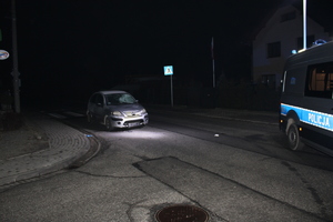 Zdjęcie przedstawia samochód stojący na przejściu dla pieszych nocą, obok radiowóz.