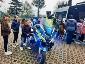 Zdjęcie przedstawia policjanta pokazującego dzieciom służbowy motocykl.