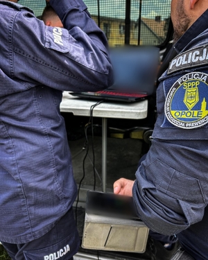 Dwóch policjantów analizuje dane na laptopie.