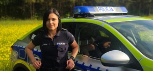 Zdjęcie kolorowe przedstawiające policjantkę i radiowóz.