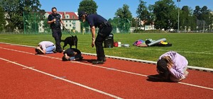 Zdjęcie kolorowe przedstawiające policjanta z psem służbowym i dzieci.