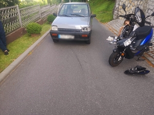 Zdjęcie kolorowe przedstawiające samochód osobowy oraz motorower.