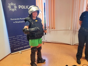Zdjęcie kolorowe przedstawiające policjantów z dziećmi  w komendzie.