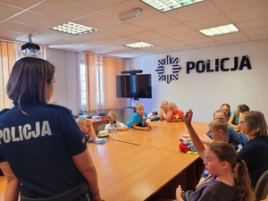 Zdjęcie kolorowe przedstawiające policjantów z dziećmi  w komendzie.