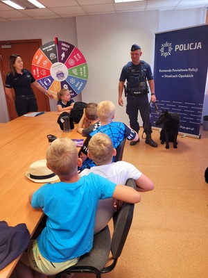 Zdjęcie kolorowe przedstawiające policjantów z dziećmi  w komendzie.