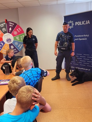 Zdjęcie kolorowe przedstawiające policjantów z dziećmi  w komendzie.