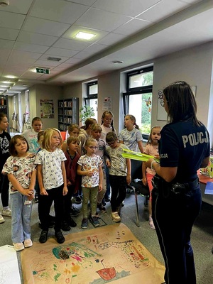 Zdjęcie przedstawiające policjantkę z dziećmi w bibliotece.