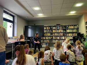 Zdjęcie przedstawiające policjantkę z dziećmi w bibliotece.