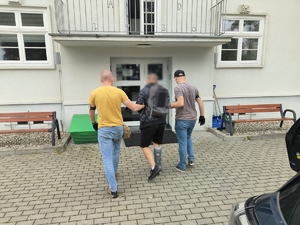 Zdjęcie kolorowe przedstawiające policjantów z zatrzymanym.
