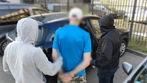 Zdjęcie kolorowe przedstawiającego policjantów prowadzących mężczyznę.