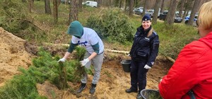 Zdjęcie przedstawia wydarzenie związane z jubileuszem 100-lecia dzielnicowych, którzy z tej okazji posadzili symboliczne 100 sadzonek w lesie.