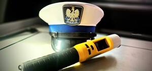 Zdjęcie przedstawia czapkę policjanta i alkomat.