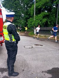 Zdjęcie przedstawia policjanta zabezpieczającego wyścig, w tle zawodnicy.