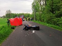Zdjęcie przedstawia motocykl, leżący na jezdni, po zdarzeniu drogowym.