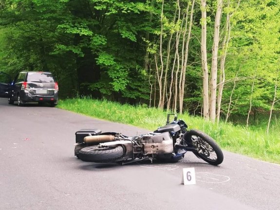 Zdjęcie przedstawia motocykl, leżący na jezdni, po zdrarzeniu drogowym.