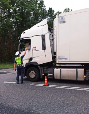 Zdjęcie przedstawia policjanta ruchu drogowego w trakcie kontroli trzeźwości kierującego.