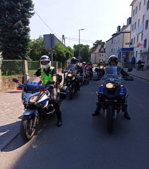 Zdjęcie przedstawia policjanta ruchu drogowego oraz motocyklistów, którzy wyjeżdżają spod budynku KPP Strzelce Opolskie.