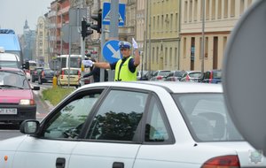 policjant ruchu drogowego kieruje ruchem otoczony przejeżdżającymi samochodami